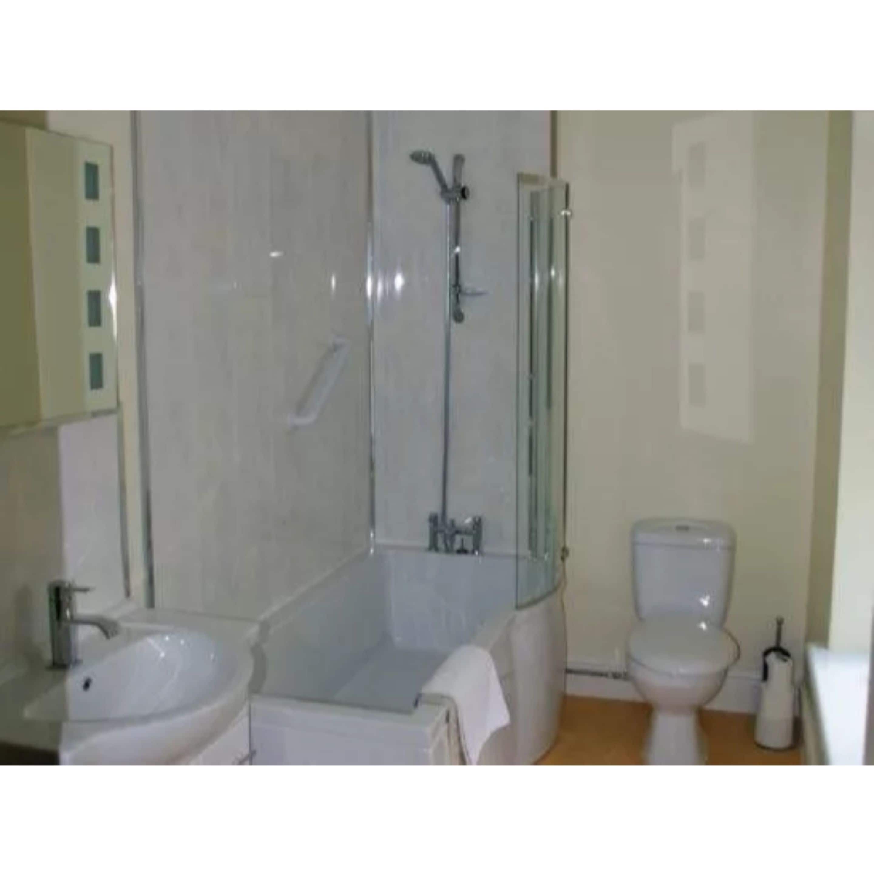 A bathroom with a glass-enclosed shower, a toilet, and a sink.