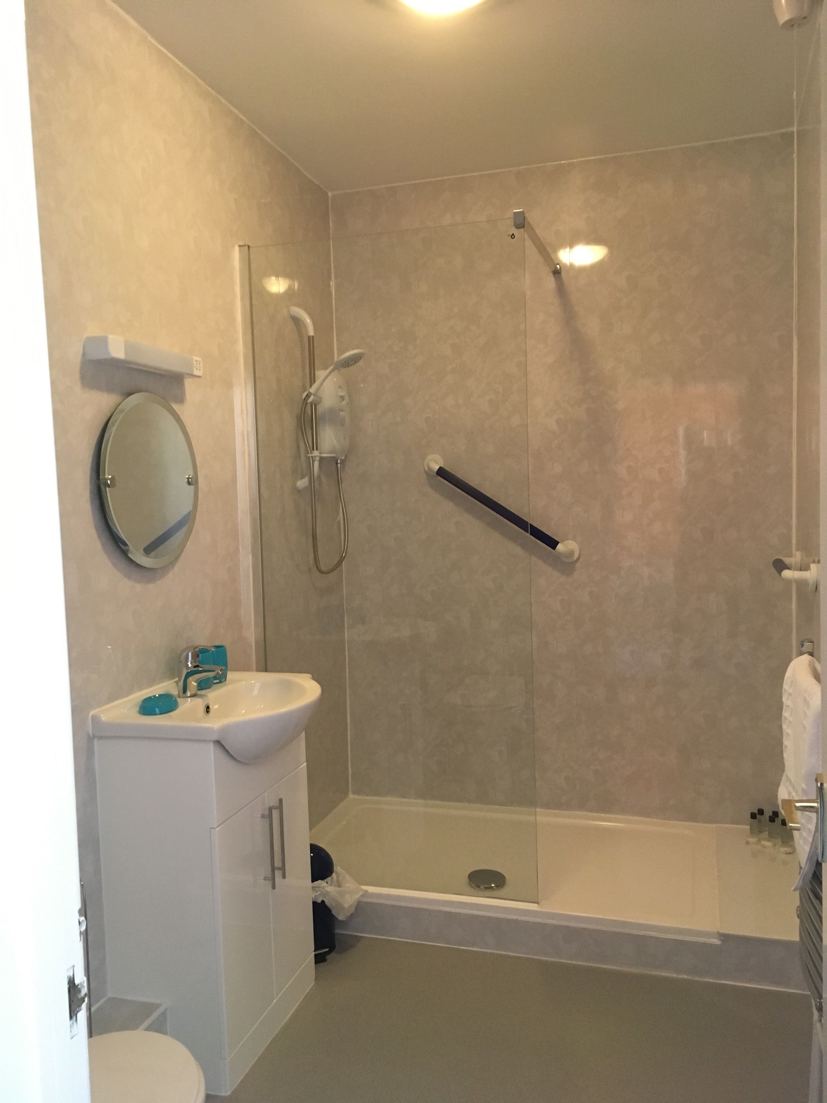 A modern bathroom with a shower, toilet, and sink.