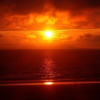 Un atardecer sobre el océano con cielo despejado.