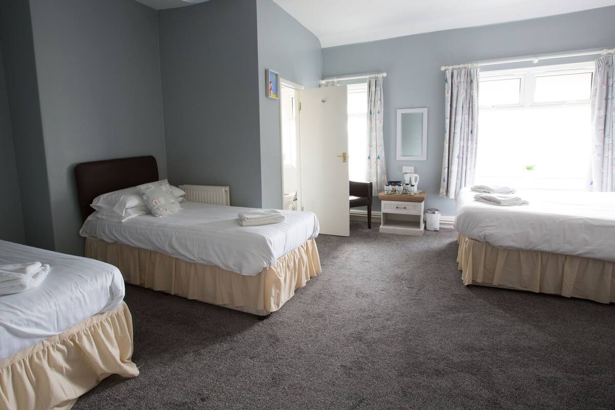 Habitación de hotel con dos camas, un escritorio, una silla y una ventana con cortinas.