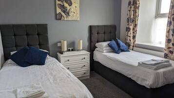 A bedroom with two beds, a nightstand, and a painting on the wall.