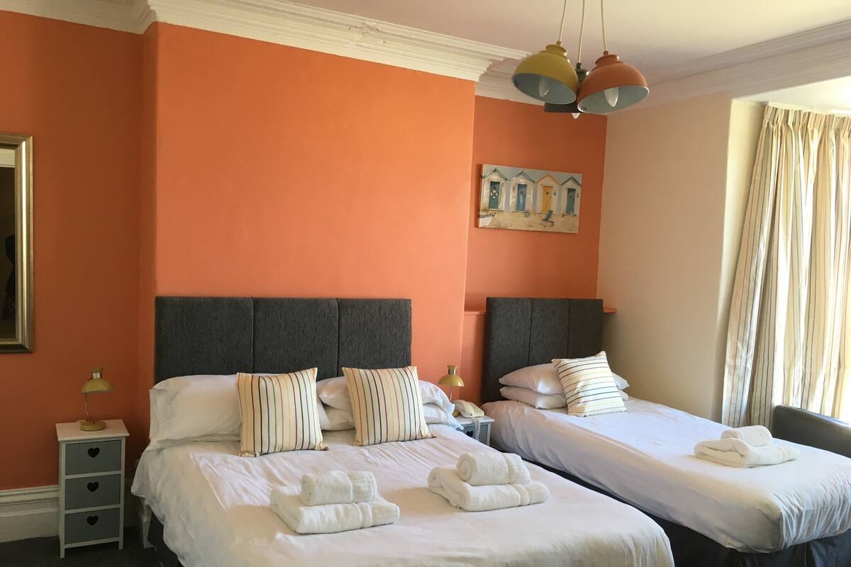 Una habitación de hotel con dos camas, un cuadro en la pared y una ventana con cortinas.