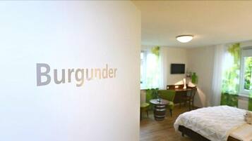 Una habitación con una cama, un escritorio y una silla. La habitación tiene una ventana con cortinas y vistas a zonas verdes.