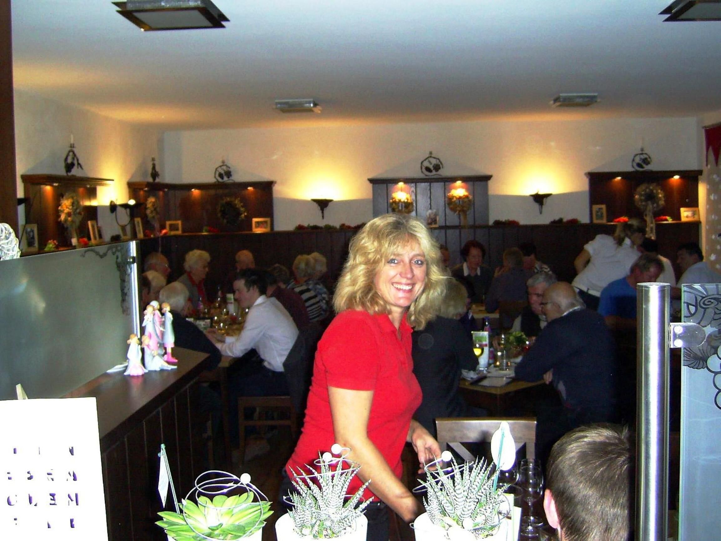 Ein Restaurantinneres mit Tischen, Stühlen und einer Bar. An der Wand befinden sich dekorative Wandleuchten.