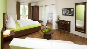 A hotel room with a bed, a desk, a chair, a sofa, a TV, and a window. - Hotel Wein-Träume (Thuengersheim)