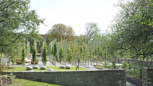 A landscaped garden with a stone wall, pathways, and neatly trimmed hedges. - Hotel Wein-Träume (Thuengersheim)