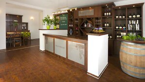 A bar area with wooden shelves, a counter, and a large barrel. - Hotel Wein-Träume (Thuengersheim)