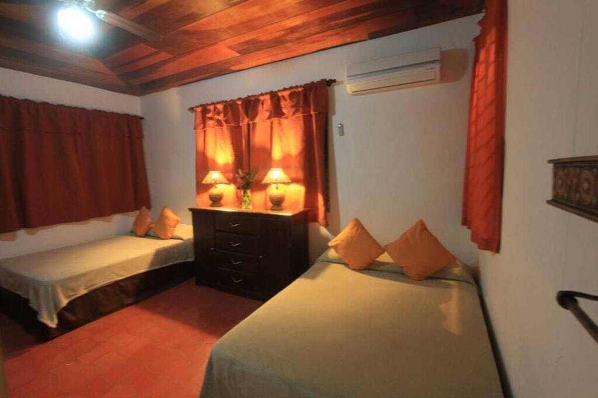 Une chambre avec deux lits simples, une commode en bois et une table de chevet avec des lampes.