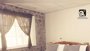 Een slaapkamer met een stenen muur, een houten bed en een raam met gordijnen.