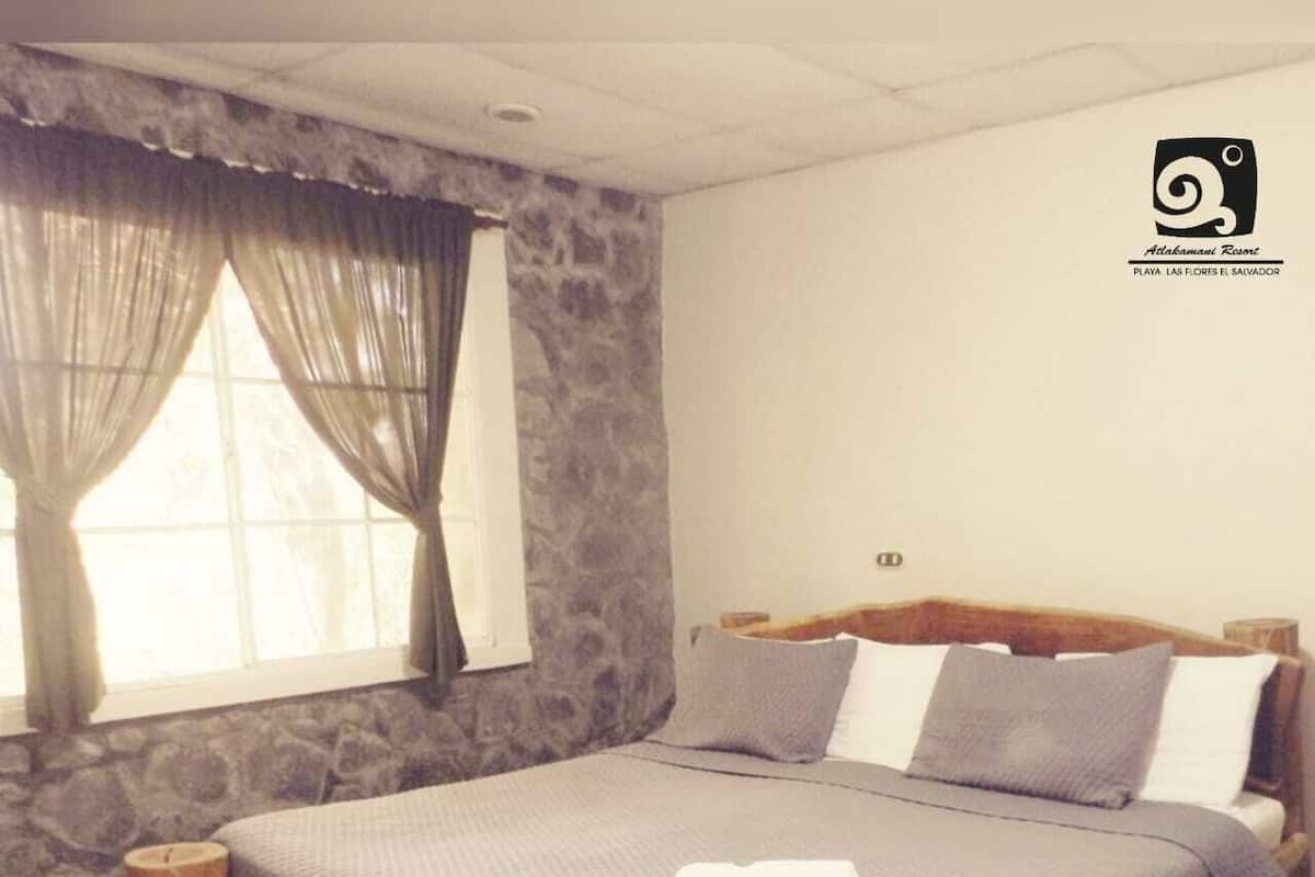 Une chambre avec un mur en pierre, un cadre de lit en bois et une fenêtre avec des rideaux.