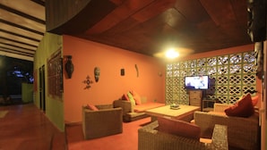 Een gezellige zithoek met rieten meubels, een flatscreen televisie en decoratieve wandkunst.