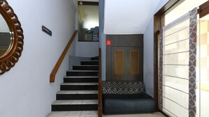 Eine Treppe mit Holzgeländer, einem Schild, das einen Aufenthaltsraum anzeigt, und einer Tür mit einem roten 'X'-Symbol.