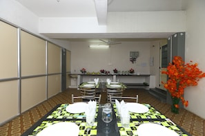 Une salle de conférence avec une table préparée pour une réunion, équipée de chaises, d’un projecteur et d’une grande fenêtre.