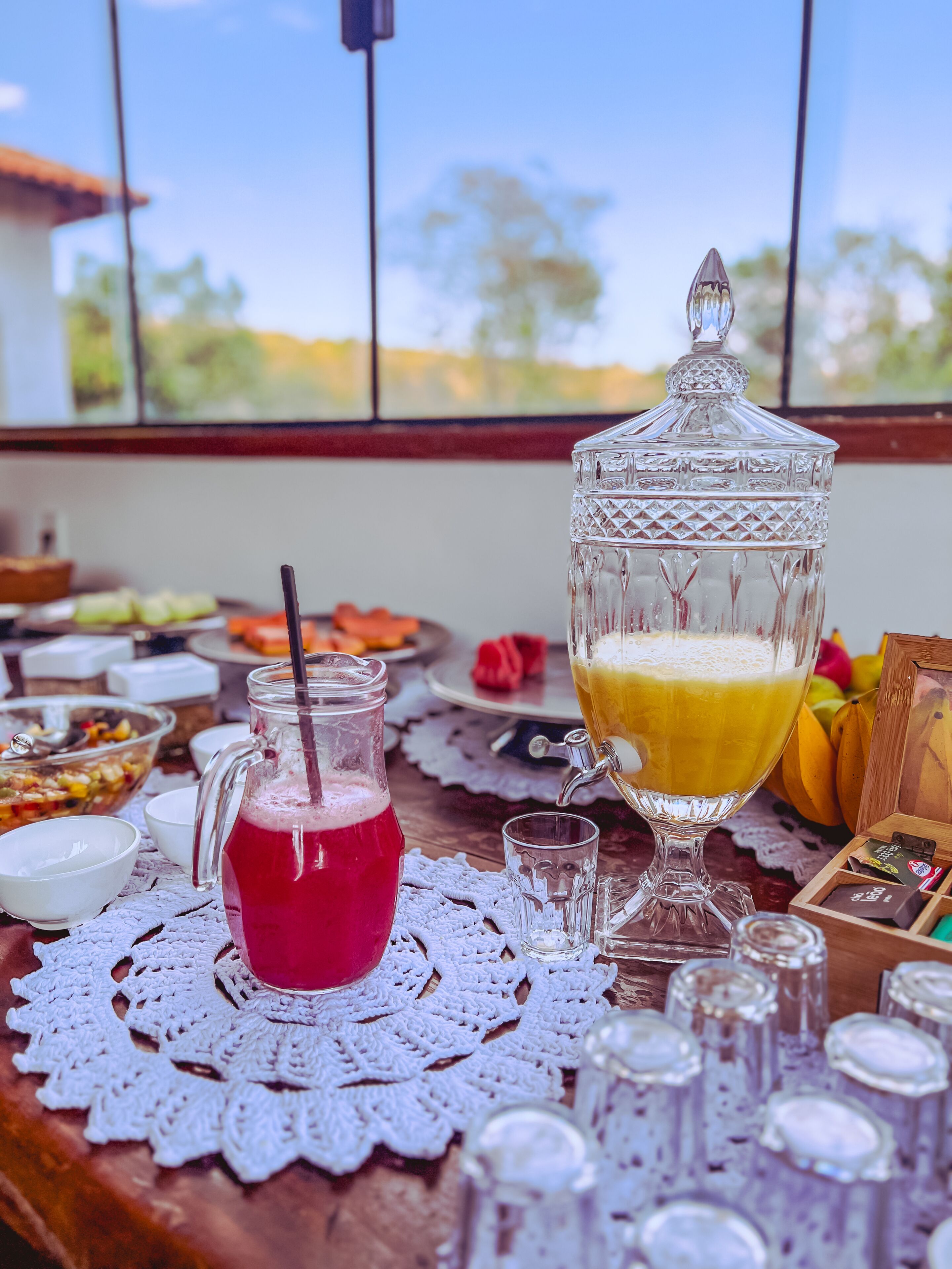 Une table avec une carafe de boisson rouge, un verre de jus d’orange et divers aliments.