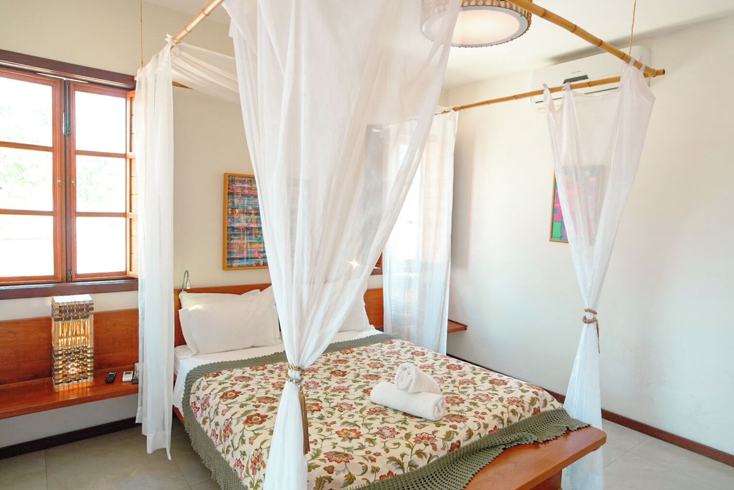 A bed with a floral bedspread, a white canopy, and a wooden headboard.