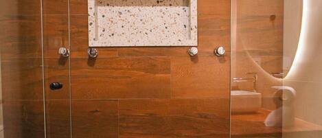 A modern shower with a wooden panel wall, a glass door, and a small shelf with a towel.