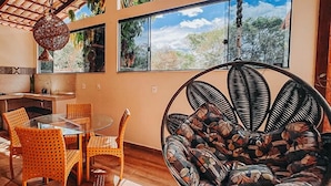 A dining area with a hanging chair, a table, and chairs. - Chalés Terraviva (Pirenópolis)