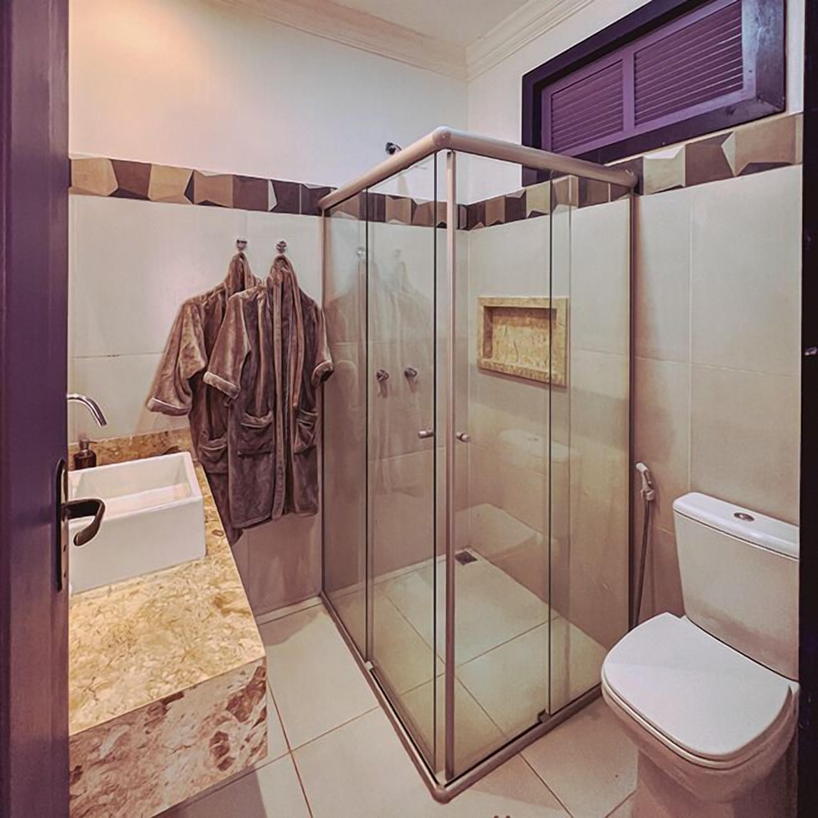 A modern bathroom with a glass-enclosed shower, a white toilet, and a marble sink.
