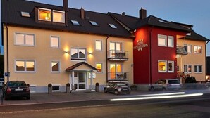 Un hôtel à la façade jaune, avec une partie rouge et un balcon.