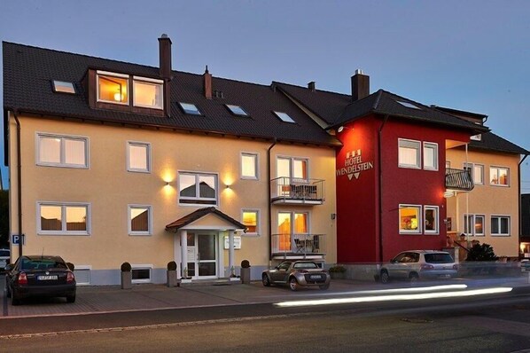 Hotellin julkisivu on keltainen, siinä on punainen osa ja parveke.