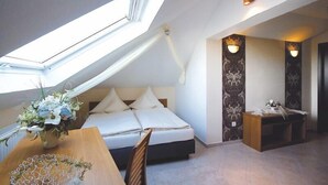 Une chambre à coucher avec un puits de lumière, un lit, une table de chevet et un vase décoratif.