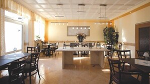 Un grand espace dédié à la salle à manger, avec un îlot central, plusieurs tables et des chaises.