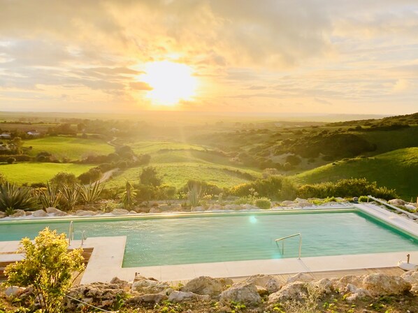 Una piscina al aire libre, sombrillas, sillones reclinables de piscina