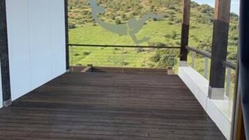 Una terraza de madera con vista a un paisaje verde y colinas.