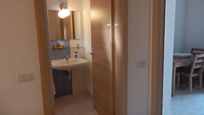 A small bathroom with a sink, mirror, and wooden door. - Borgo Camicia In (Barcellona Pozzo di Gotto)