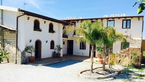 A courtyard with a pool, surrounded by a building with arched windows and a small tree. - Borgo Camicia In (Barcellona Pozzo di Gotto)