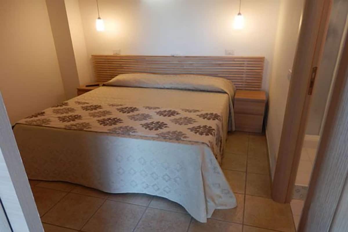 A bedroom with a bed, bedside tables, and a headboard.