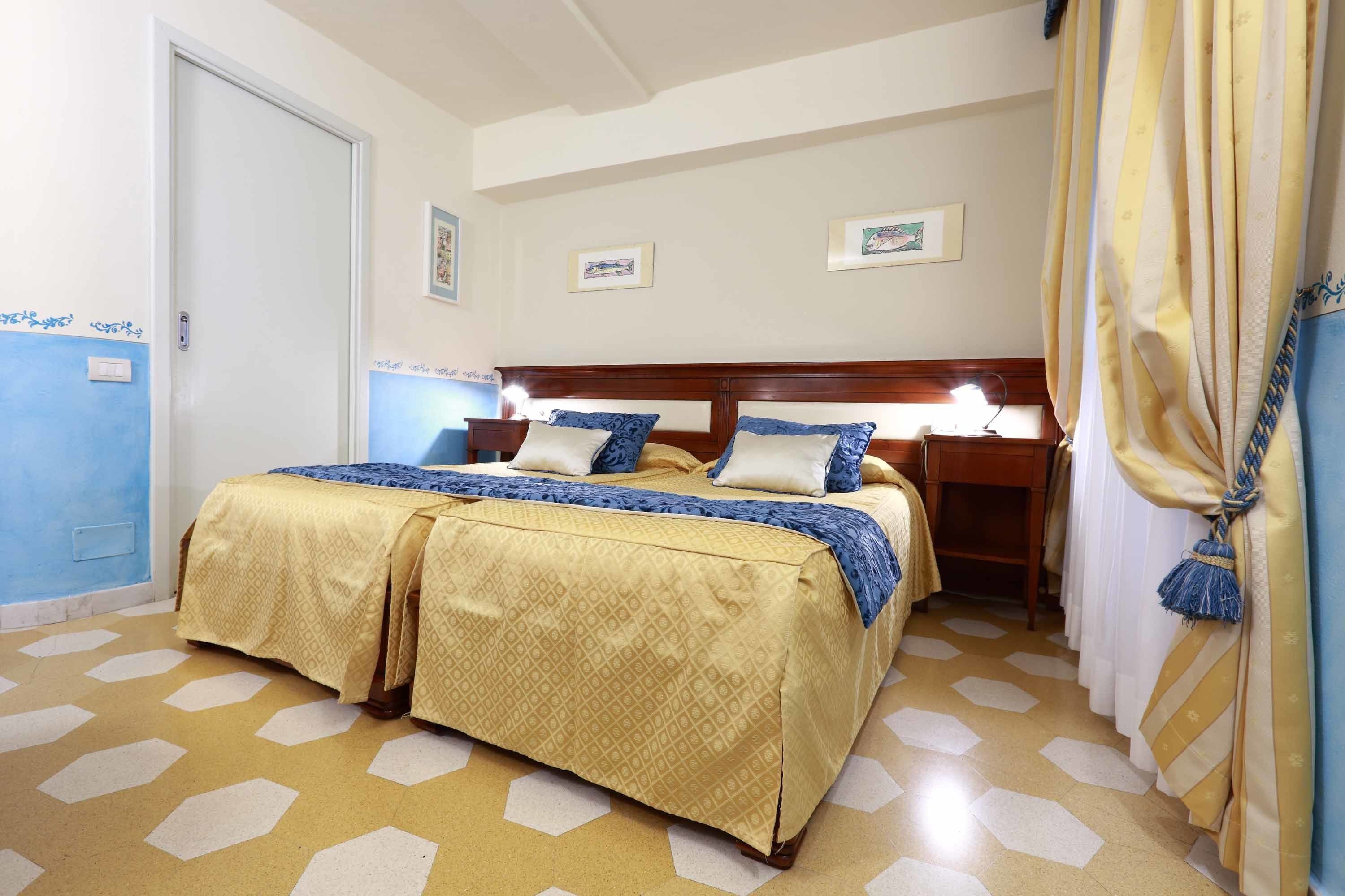 Una camera d'albergo con un letto matrimoniale, un comodino e una tenda.
