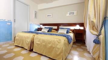 Una camera d'albergo con un letto matrimoniale, un comodino e una tenda.