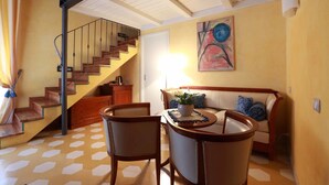 Una sala de estar con una escalera, un sofá, una mesa de centro y un cuadro en la pared.