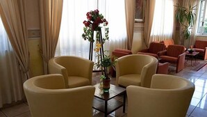 Una habitación con dos sillones amarillos, una pequeña mesa con un jarrón de flores y una planta en maceta.