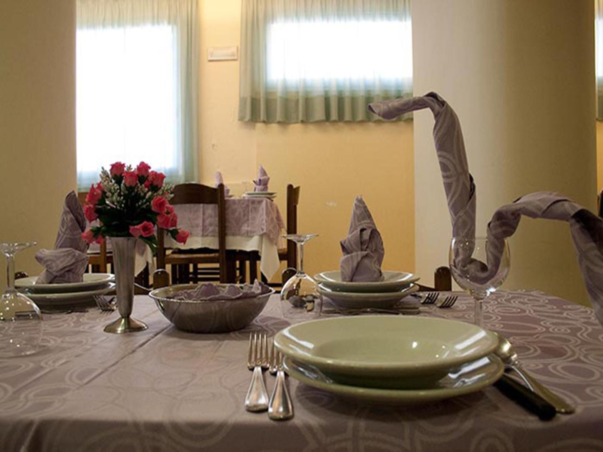 Una mesa de comedor dispuesta con platos, cubiertos y un florero.