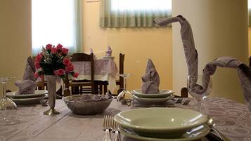 Una mesa de comedor dispuesta con platos, cubiertos y un florero.