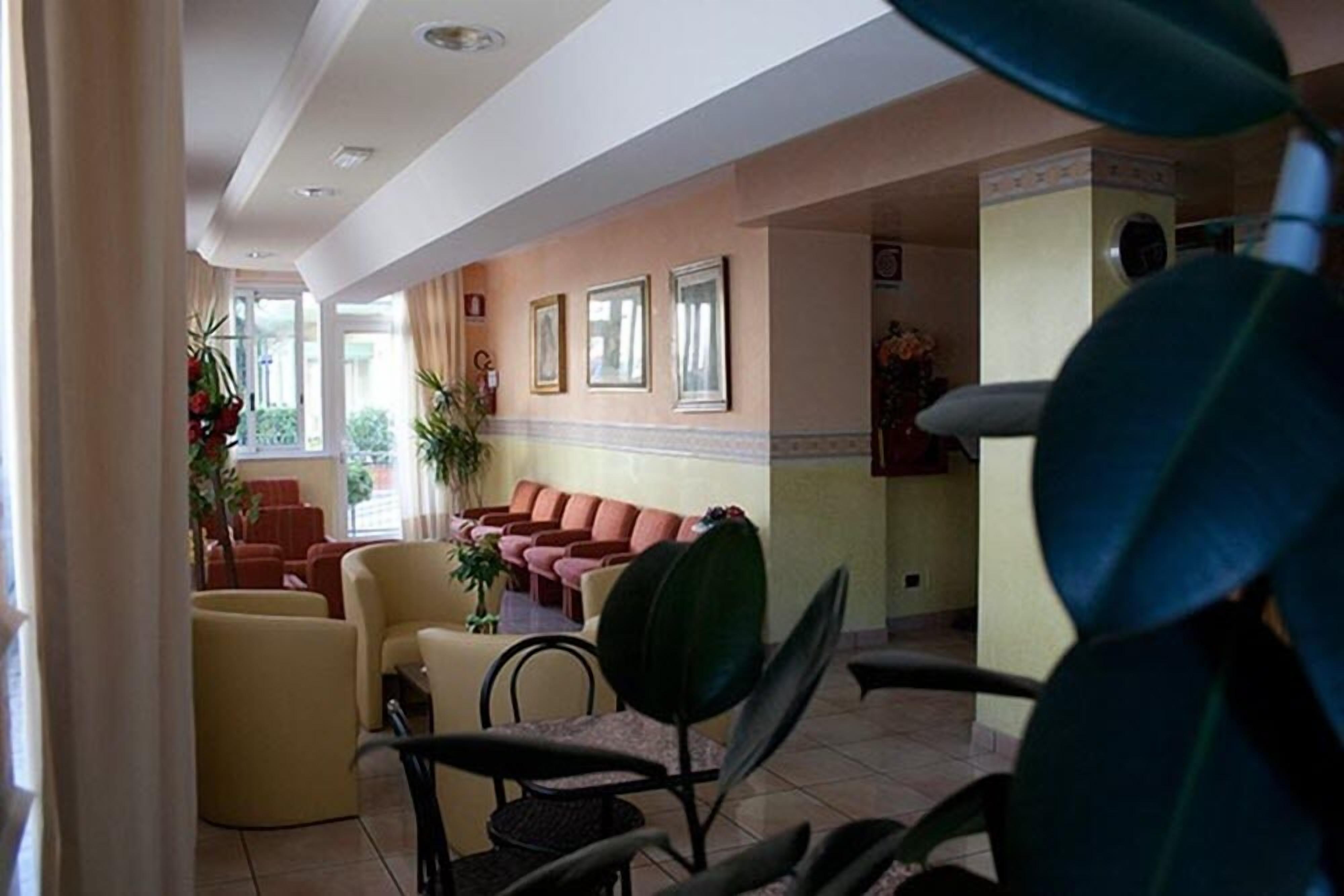 Un vestíbulo de hotel con mostrador de recepción, zona de estar y vistas al exterior.