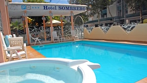 Zona de piscina en el Hotel SOMBRERO, con sillas de descanso y un jacuzzi.