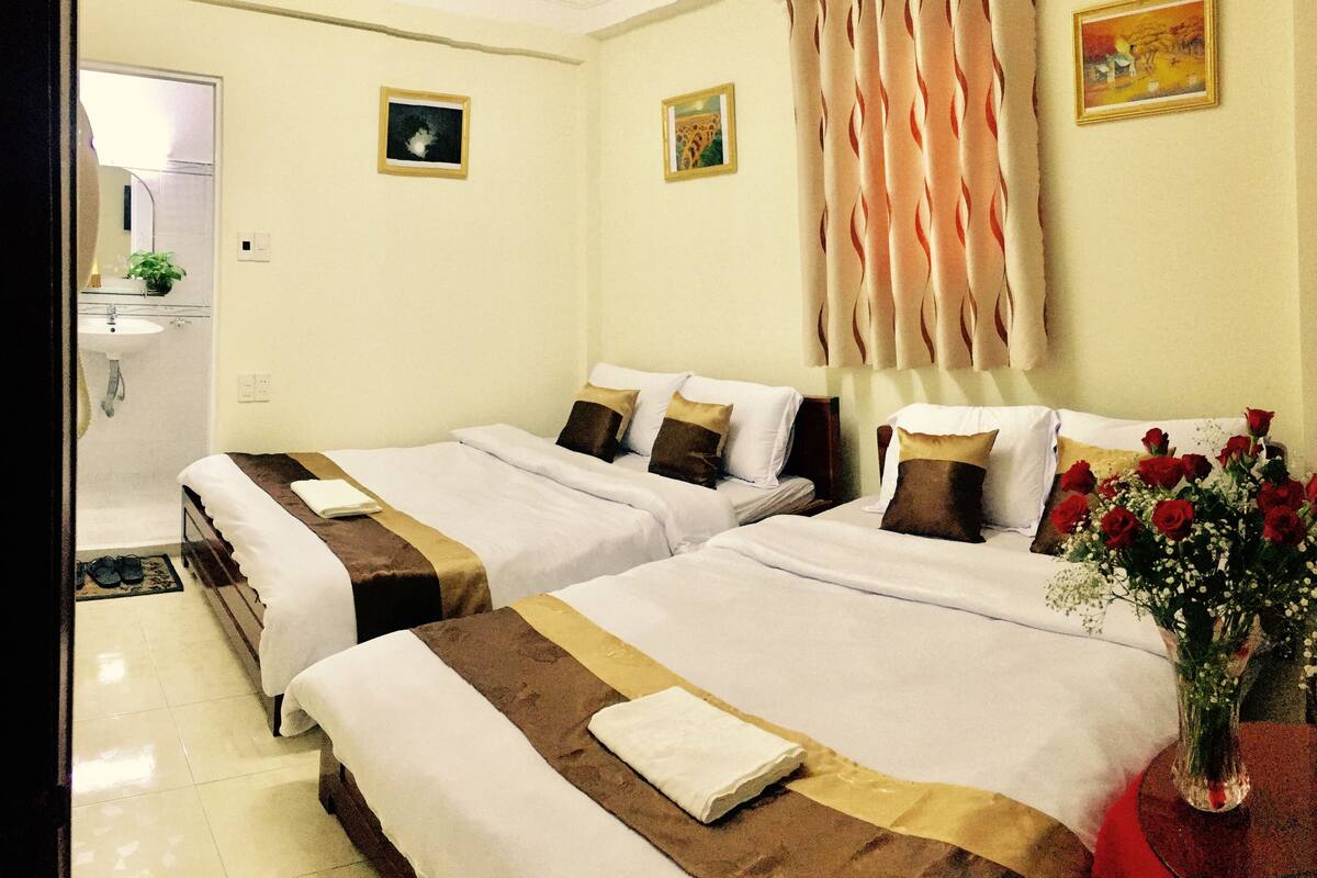 A hotel room with two beds, a bathroom, and a painting on the wall.
