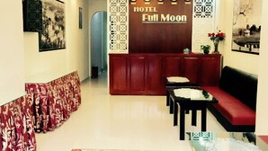 A hotel lobby with a reception desk, a red sofa, a patterned carpet, and a clock on the wall. - Full Moon Da Lat Hotel (Cam Ly - Da Lat)