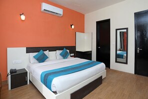 Ein Hotelzimmer mit Bett, Nachttisch, Wandklimaanlage und Spiegel.
