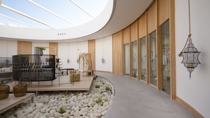 A modern interior with a curved ceiling, a seating area with a wooden deck, and a stone pathway. - Aelia Wellness Retreat (Analiontas)