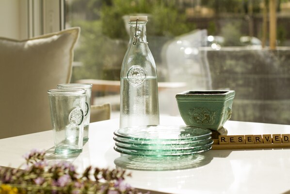A table with a glass bottle, two glasses, a green bowl, and a word "RESERVED" on a tray. - Aelia Wellness Retreat (Analiontas)