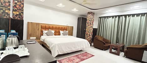 A modern hotel room with a large bed, a wooden headboard, a desk with a coffee maker, and a red rug.
