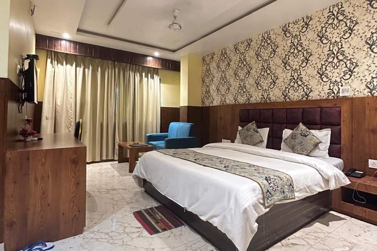 Quarto de hotel com uma cama grande, cabeceira de madeira, escrivaninha e uma cadeira.