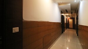 Um corredor com parede de painel de madeira, um interruptor de luz e uma porta no final.