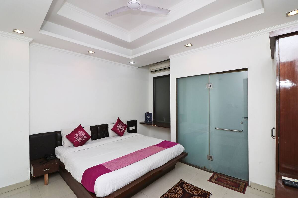 Une chambre à coucher comprenant un lit, une table de chevet, une commode, une armoire et un ventilateur de plafond.