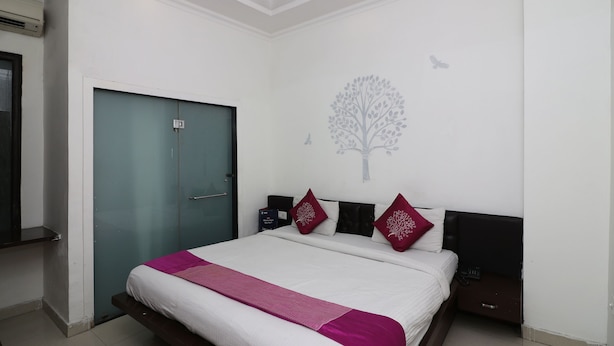 Quarto com cama, guarda-roupa, mesa de cabeceira e um objeto decorativo na parede.