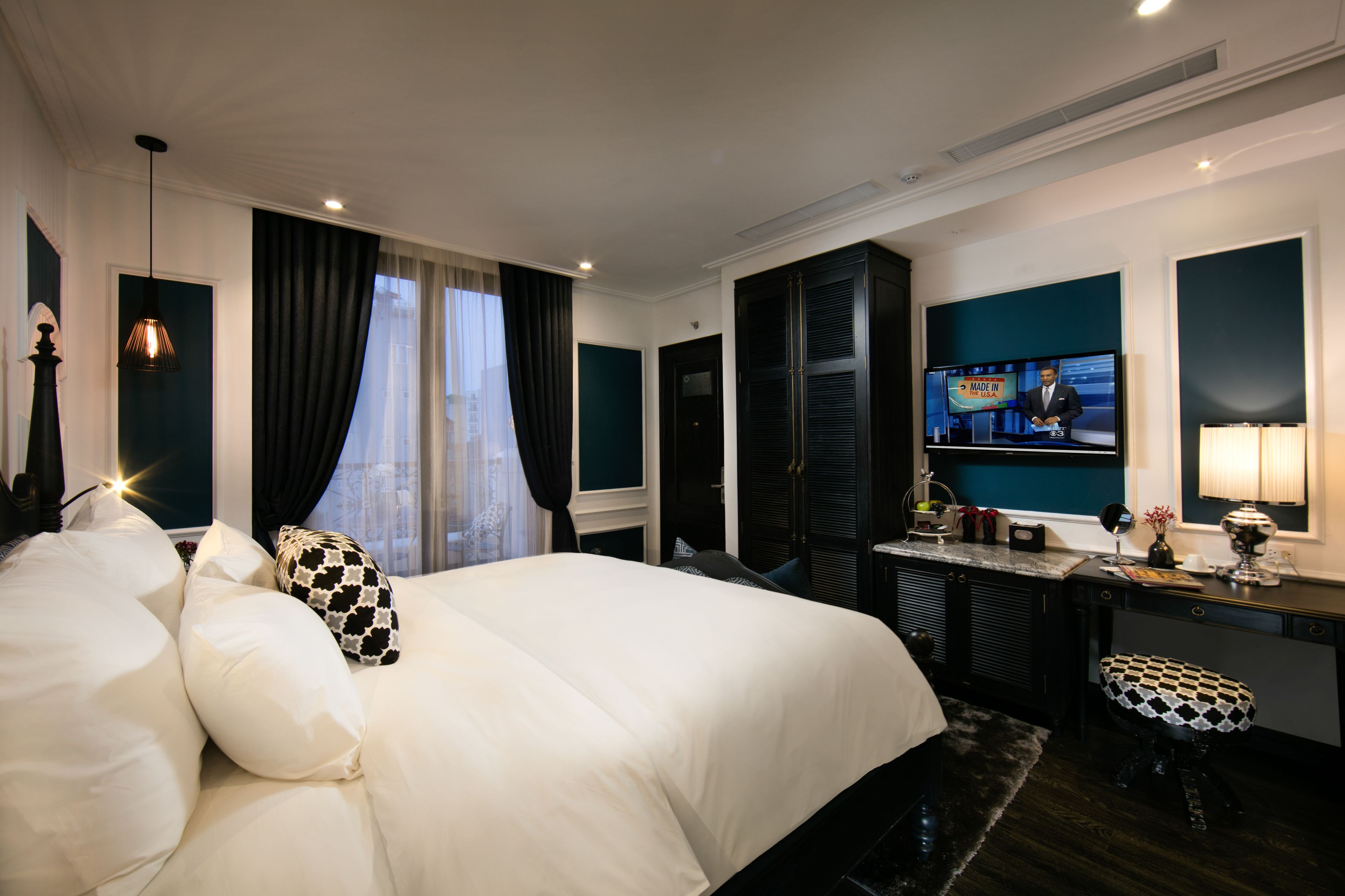 Habitación de hotel con una cama grande, un escritorio con televisor y vistas a la ciudad desde la ventana.
